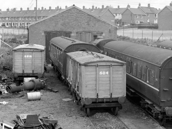 July 1977: Guinness Vans 2518 (derailed and acting as a wood store) and 504 in front of the shed at Whitehead. (C.P. Friel)