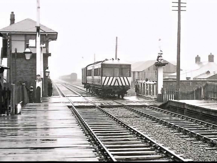 24/4/1964: The railcar with a brown van in tow is seen passing Ballyclare Junction on the 12:05 York Road to Cullybackey. In the distant siding is a rake of stored steam carriages. (R. Whitford).