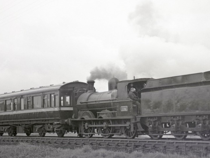 5/5/1968:  Driver Mosey Simpson mops his brow on the footplate of No.186 while waiting for the road at Knockmore Junction. Carriages 150 and 198 make up the train. (C.P. Friel)